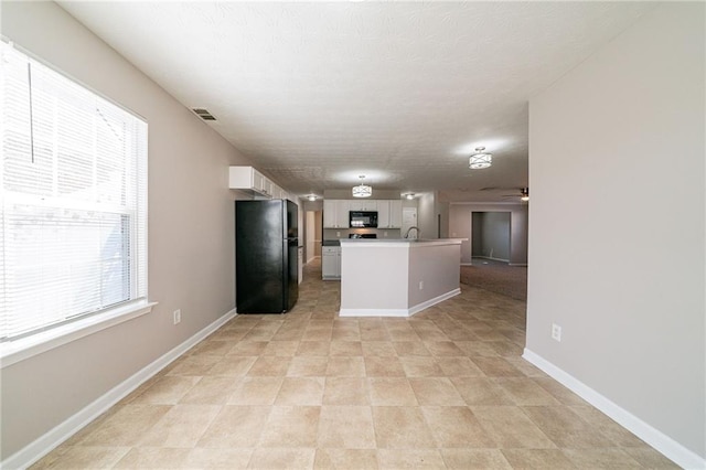 kitchen with open floor plan, white cabinets, ceiling fan, black appliances, and baseboards