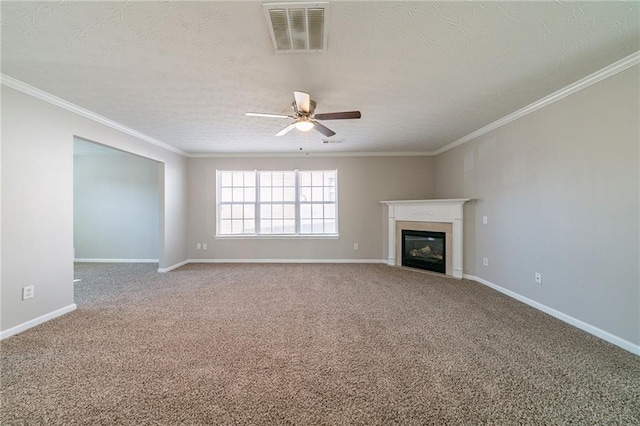 unfurnished living room featuring carpet flooring, visible vents, baseboards, ornamental molding, and a glass covered fireplace