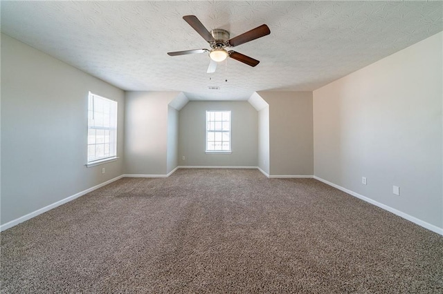 spare room with a textured ceiling, carpet, and baseboards