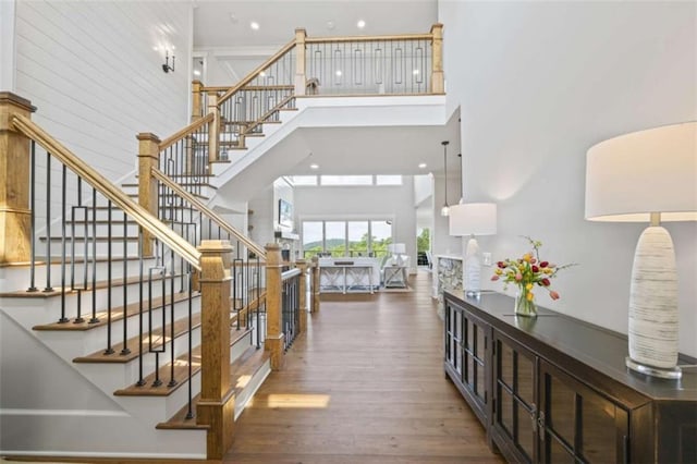 staircase featuring a towering ceiling and hardwood / wood-style flooring