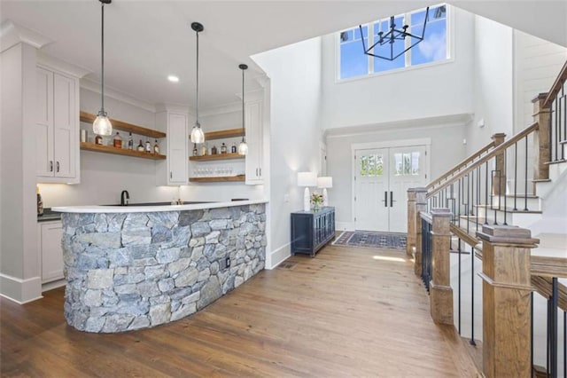 bar featuring hardwood / wood-style floors, white cabinetry, hanging light fixtures, and ornamental molding