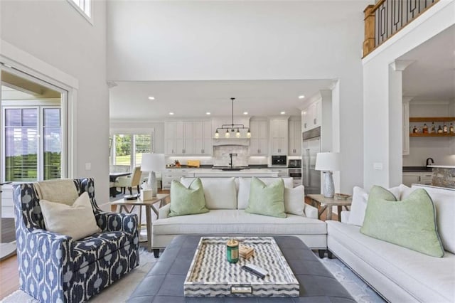 living room with sink, a high ceiling, and light hardwood / wood-style flooring