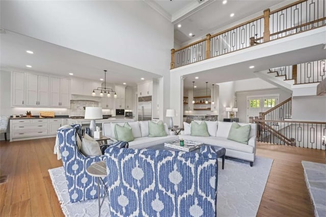 living room with crown molding, a high ceiling, and light wood-type flooring