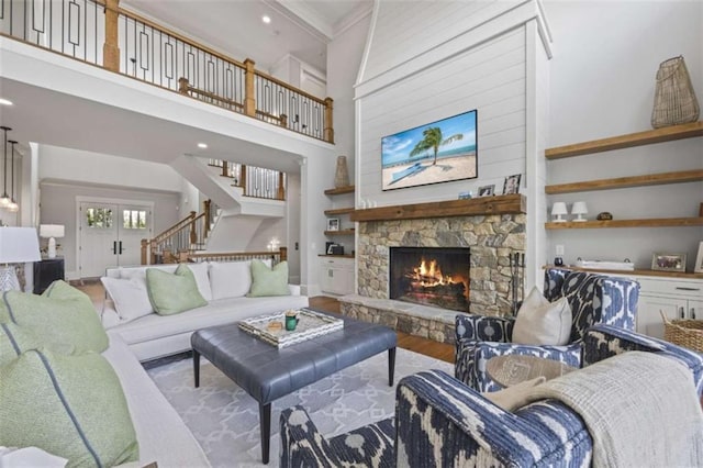 living room with a stone fireplace, light hardwood / wood-style flooring, and a high ceiling