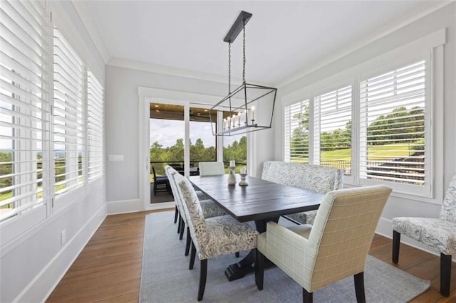 dining space featuring wood-type flooring, ornamental molding, and an inviting chandelier