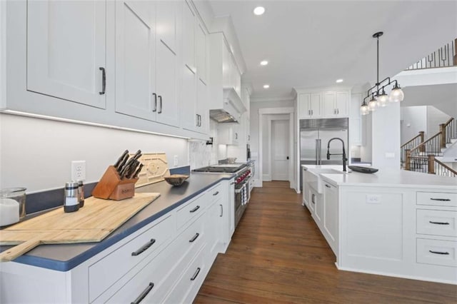 kitchen featuring dark hardwood / wood-style flooring, a kitchen island with sink, pendant lighting, high quality appliances, and white cabinets