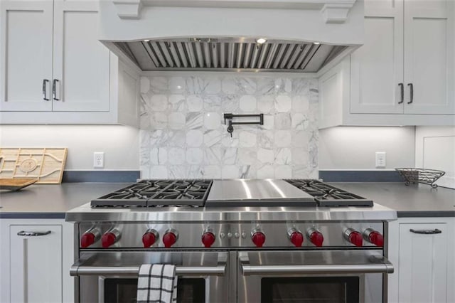 kitchen featuring tasteful backsplash, white cabinetry, range with two ovens, and custom range hood