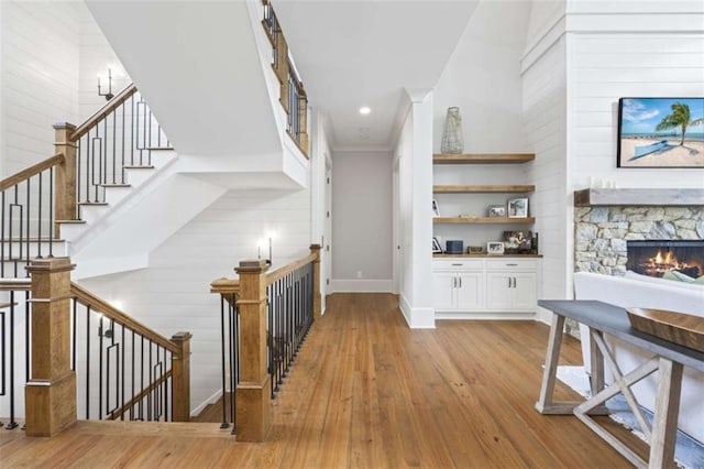 bar with light hardwood / wood-style floors, white cabinetry, a fireplace, and a high ceiling