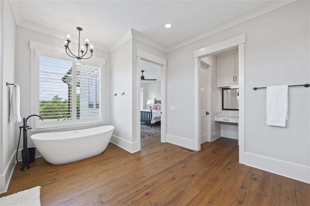 bathroom with ceiling fan with notable chandelier, hardwood / wood-style flooring, a bathtub, and crown molding