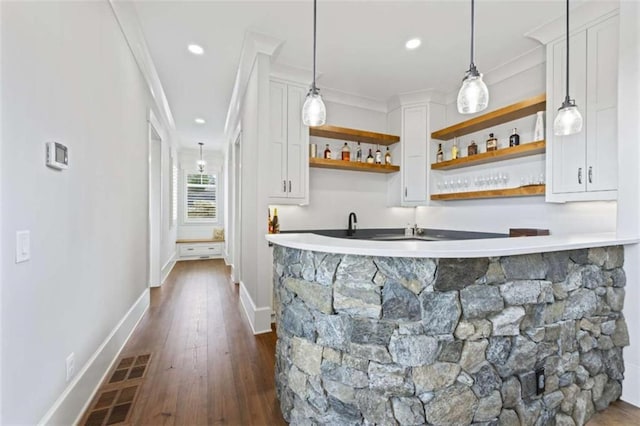 bar featuring pendant lighting, dark wood-type flooring, white cabinetry, and crown molding