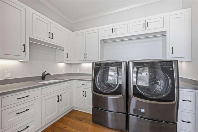 clothes washing area with cabinets, ornamental molding, sink, washing machine and dryer, and dark hardwood / wood-style floors