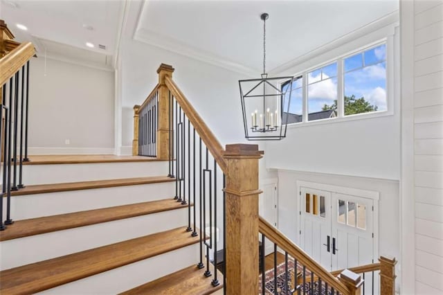 staircase featuring an inviting chandelier and ornamental molding