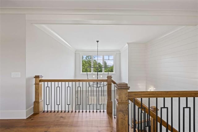 hallway featuring hardwood / wood-style floors, ornamental molding, and an inviting chandelier