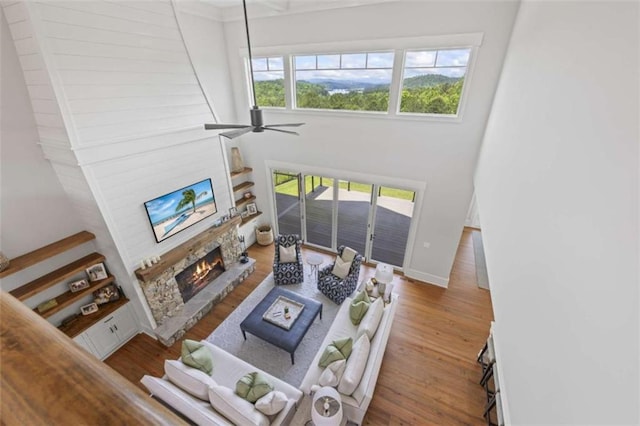 living room with hardwood / wood-style floors, ceiling fan, and a fireplace