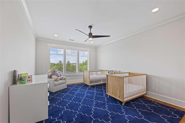 unfurnished bedroom featuring a crib, ceiling fan, and ornamental molding