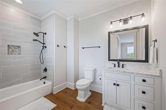 full bathroom with vanity, tiled shower / bath, hardwood / wood-style flooring, toilet, and ornamental molding