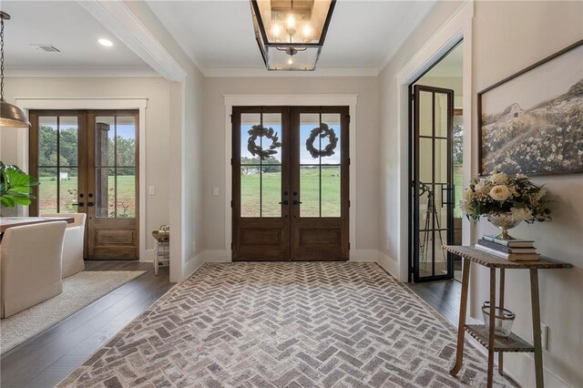 foyer entrance with french doors, ornamental molding, and dark wood-type flooring