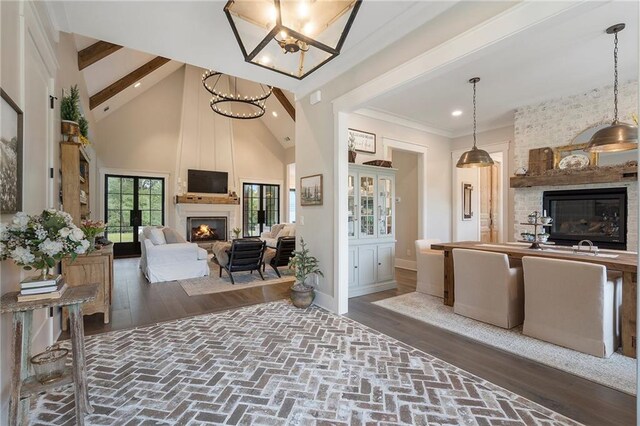 living room featuring dark hardwood / wood-style flooring, an inviting chandelier, high vaulted ceiling, beamed ceiling, and a fireplace