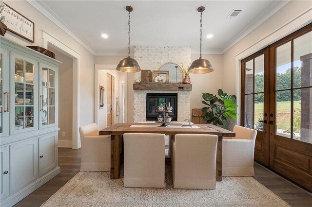 dining area with ornamental molding, french doors, wood-type flooring, and a brick fireplace