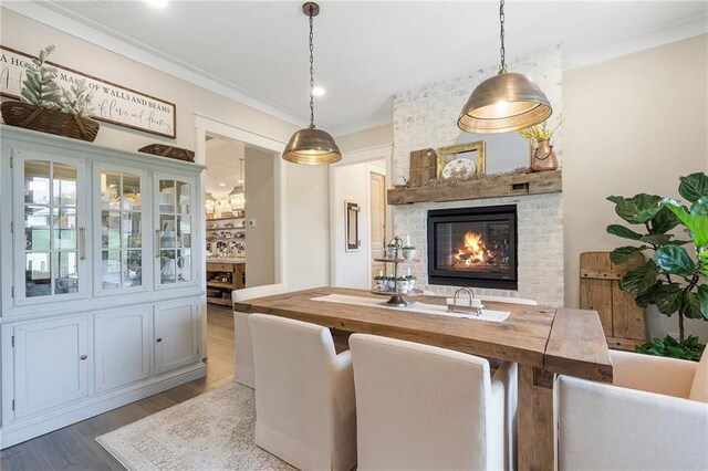 dining space with dark hardwood / wood-style flooring, crown molding, and a brick fireplace