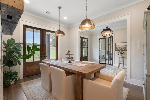 dining space with dark hardwood / wood-style flooring, crown molding, and french doors