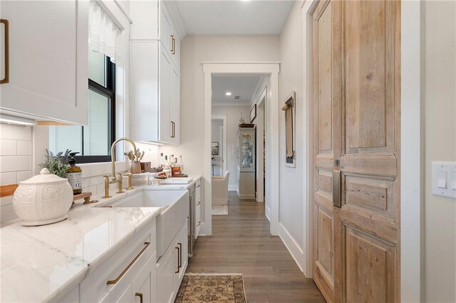 kitchen featuring light stone countertops, light hardwood / wood-style floors, white cabinetry, and tasteful backsplash