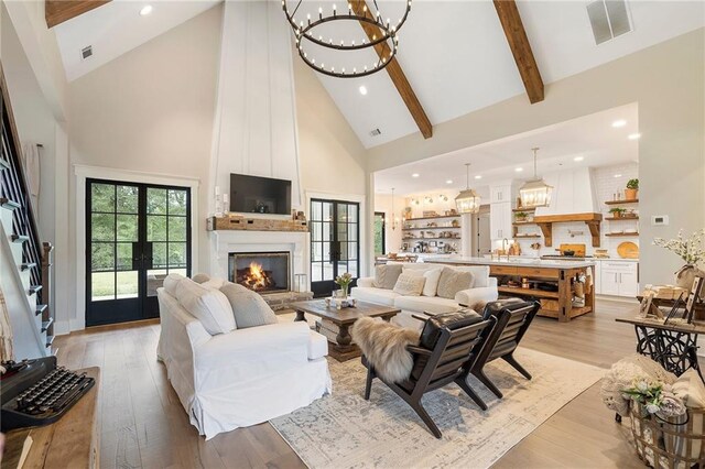 living room featuring high vaulted ceiling, french doors, light hardwood / wood-style flooring, a fireplace, and beamed ceiling