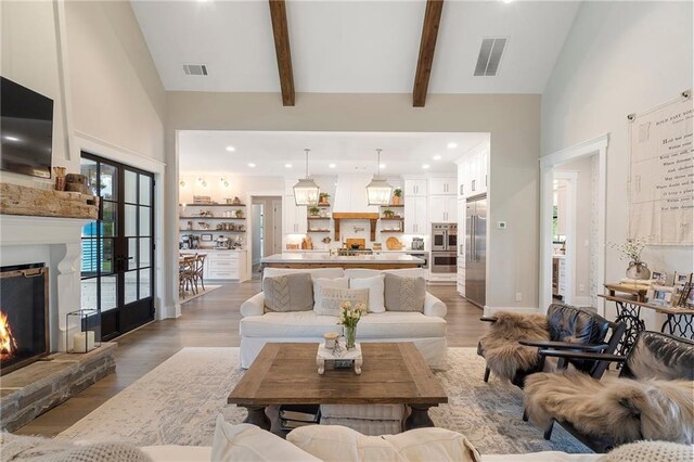 living room featuring a fireplace, hardwood / wood-style floors, high vaulted ceiling, and beam ceiling