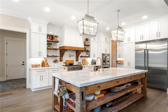 kitchen featuring appliances with stainless steel finishes, dark hardwood / wood-style flooring, decorative light fixtures, and white cabinetry