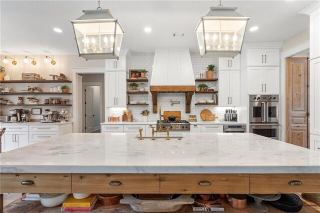 kitchen with white cabinets, custom range hood, stainless steel double oven, and hanging light fixtures