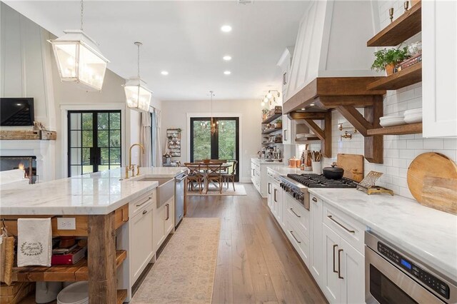 kitchen featuring light stone counters, stainless steel appliances, hardwood / wood-style floors, white cabinetry, and hanging light fixtures