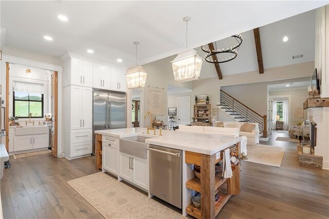 kitchen with plenty of natural light, stainless steel appliances, decorative light fixtures, and sink