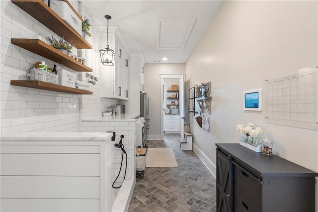 kitchen with white cabinets, decorative backsplash, and hanging light fixtures