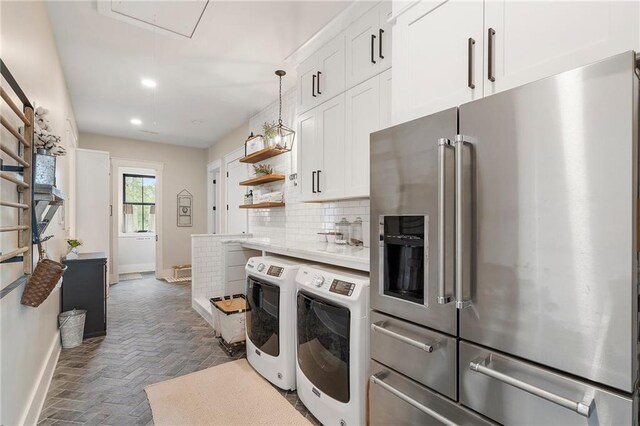 kitchen featuring pendant lighting, backsplash, separate washer and dryer, high end fridge, and white cabinetry