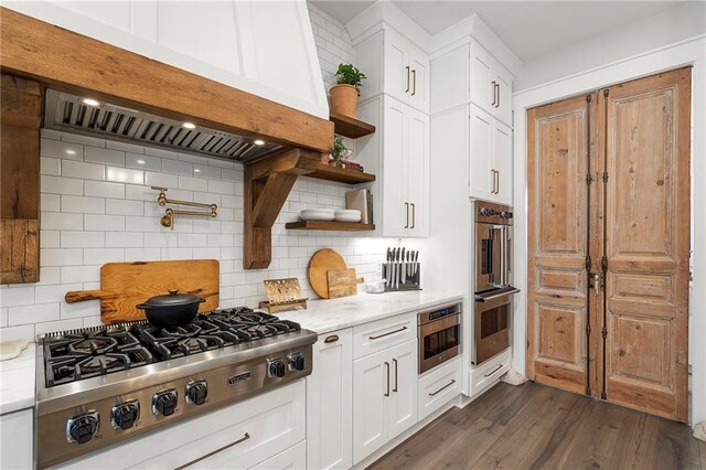 kitchen with custom exhaust hood, white cabinets, dark hardwood / wood-style floors, decorative backsplash, and appliances with stainless steel finishes