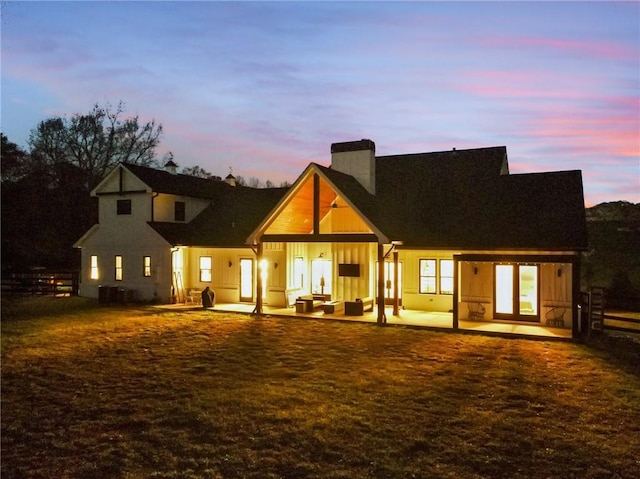 back house at dusk with an outdoor living space and a patio