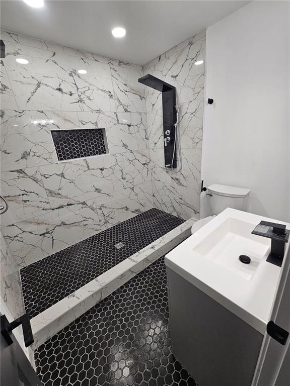 bathroom featuring toilet, sink, and a tile shower