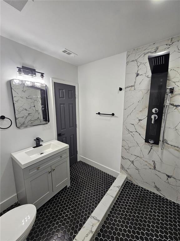 bathroom with walk in shower, vanity, toilet, and tile walls