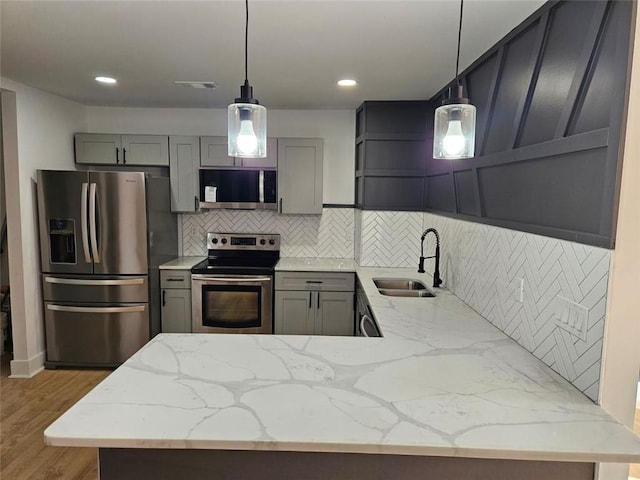 kitchen with sink, stainless steel appliances, light hardwood / wood-style flooring, pendant lighting, and gray cabinets