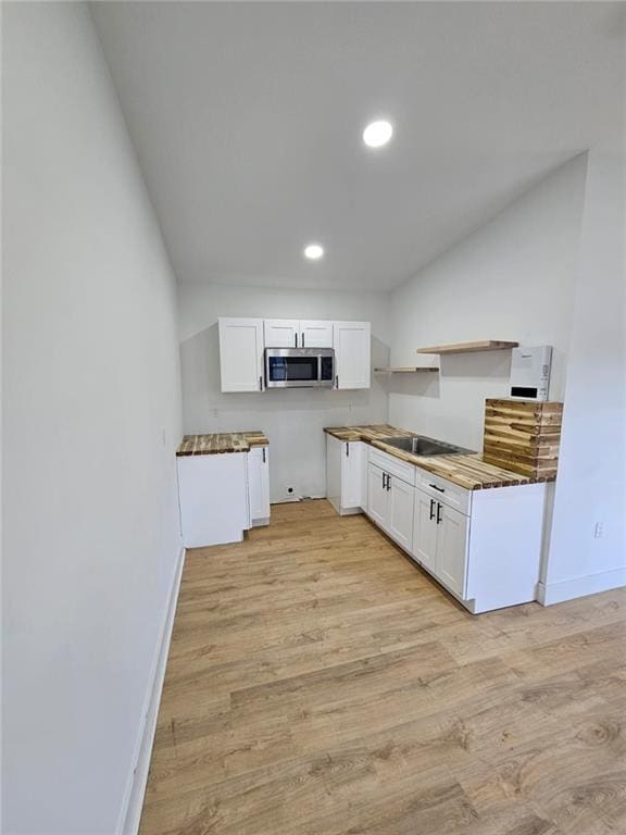 kitchen with light hardwood / wood-style flooring, white cabinets, and black electric stovetop