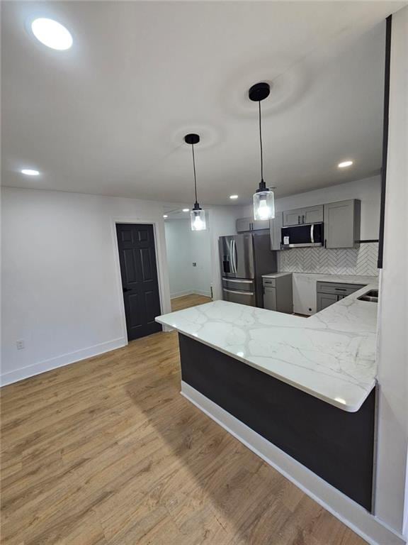 kitchen with gray cabinets, tasteful backsplash, decorative light fixtures, light hardwood / wood-style floors, and stainless steel appliances