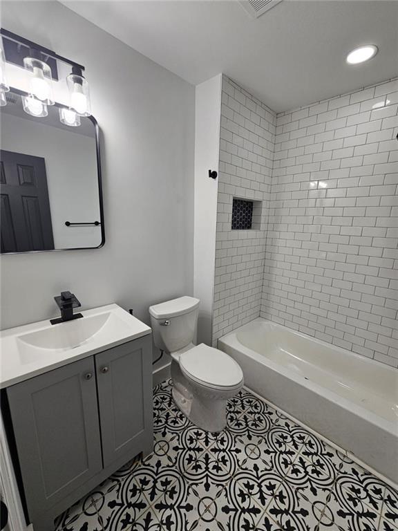 full bathroom featuring tile patterned flooring, vanity, toilet, and tiled shower / bath combo