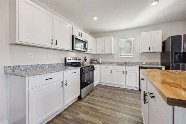 kitchen featuring butcher block countertops, white cabinetry, wood-type flooring, and appliances with stainless steel finishes