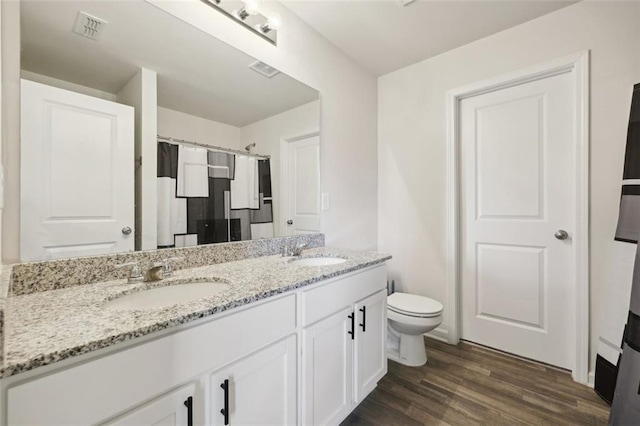 bathroom featuring wood-type flooring, vanity, toilet, and curtained shower