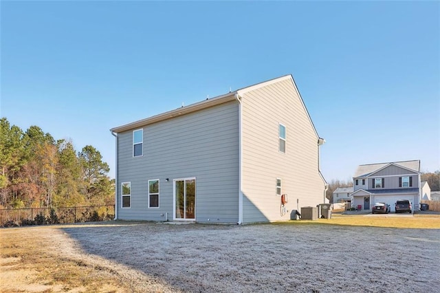 rear view of property with central AC unit and a garage