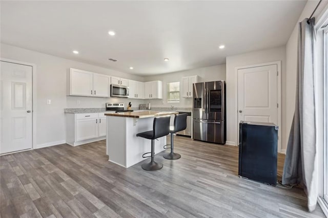 kitchen featuring white cabinets, a center island, light wood-type flooring, and stainless steel appliances