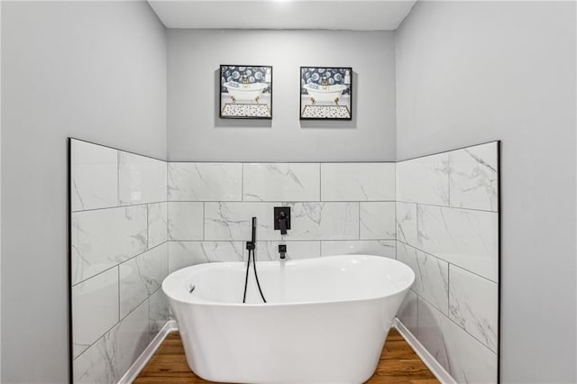 bathroom featuring hardwood / wood-style flooring, tile walls, and a washtub