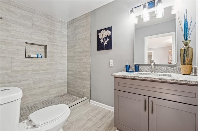 bathroom with vanity, toilet, and a tile shower