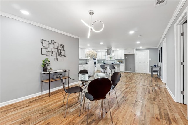 dining space with ornamental molding and light hardwood / wood-style floors