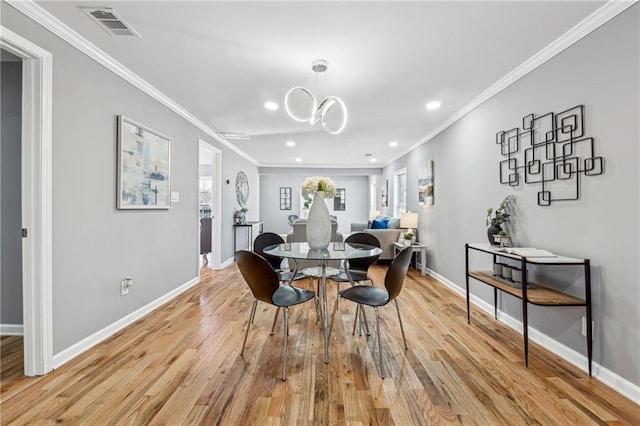 dining area with crown molding, light hardwood / wood-style floors, and a chandelier